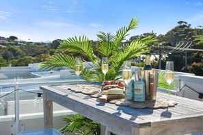 Una terraza en la azotea con una mesa de madera dispuesta con copas de vino, una botella de vino y una botella de champán.