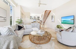 A modern living room with a sofa, a round coffee table, and a staircase.
