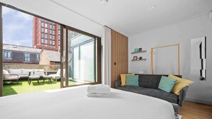 Et moderne soveværelse med en stor seng, en sofa og en skydedør, der fører ud til en balkon.