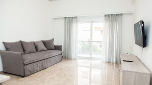 A modern living room with a grey sofa, a wooden cabinet, and a TV mounted on the wall. - Glamorous Apt in central Athens (Athens)