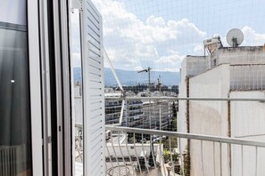 A view from a window overlooking a construction site with a metal fence, a satellite dish, and a mountainous backdrop. - Brand new 1 Bd Apt in Kolonaki (Athens)