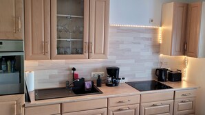 A modern kitchen with wooden cabinets, a black countertop, a built-in oven, and a coffee maker.