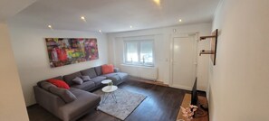 A modern living room with a grey sectional sofa, a small white coffee table, and a colorful abstract painting on the wall. - Berg Messe EG, 2,5 Zimmer, Homeoffice, W-lan (Bergisch Gladbach)