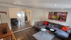A modern living room with a grey sofa, two white side tables, a grey rug, and a colorful abstract painting on the wall.
