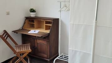 Un'area di lavoro compatta con una scrivania in legno, una sedia e una pianta in vaso.