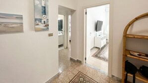 Passadís amb sòl de rajola, una prestatgeria de fusta i una porta que dóna a un bany.