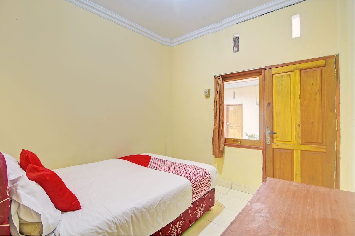 Una habitación con una cama, una mesa de madera y una puerta.