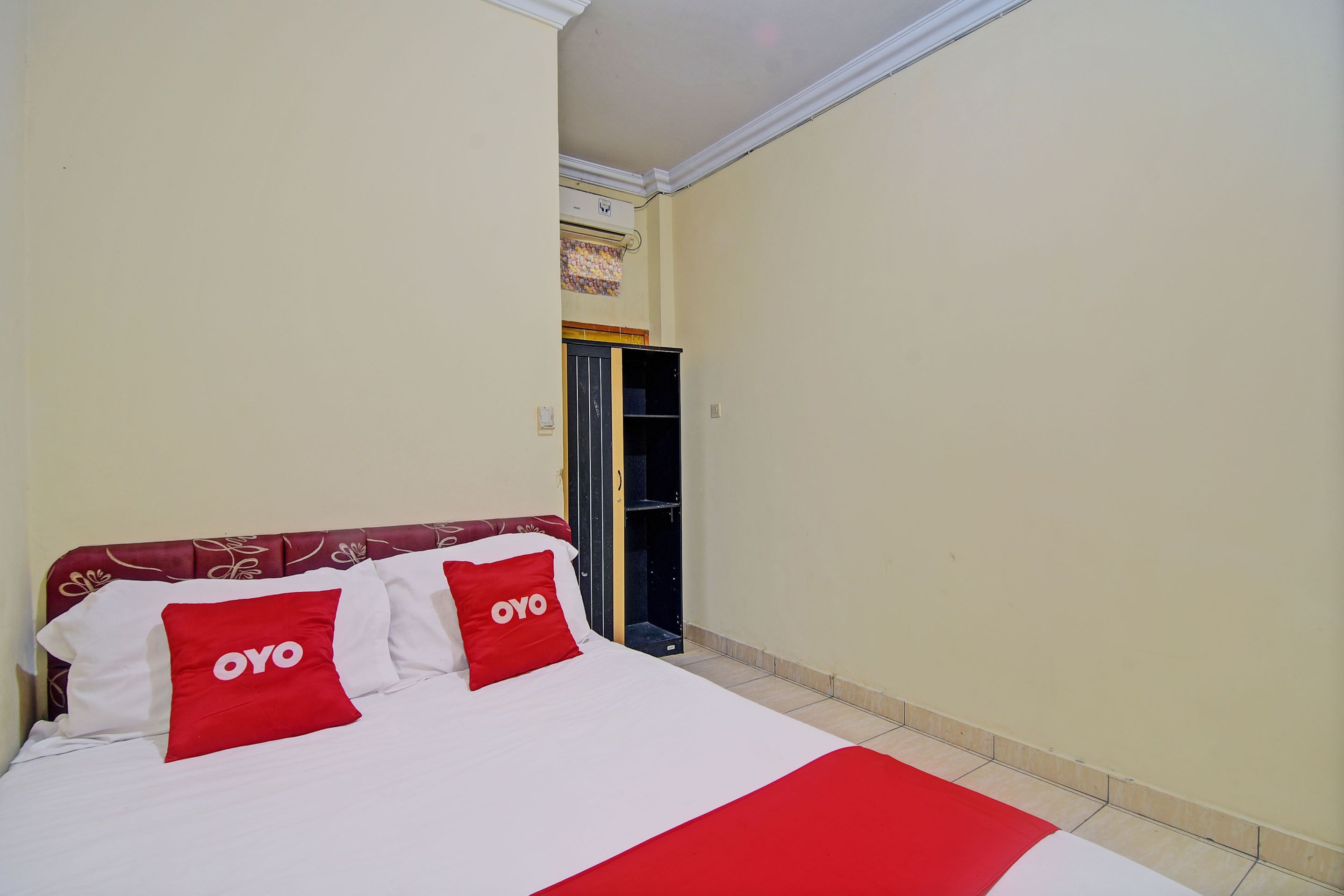 A hotel room with a bed, a wardrobe, and a door leading to a bathroom.