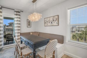 A dining area with a dark wooden table, wicker chairs, a bench, a chandelier, and a painting on the wall. - Walk to the beach-Community Pool/Seasonally Heated (Santa Rosa Beach)