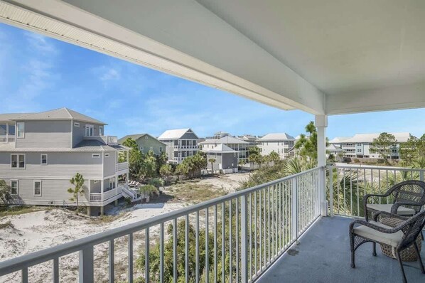Varanda com vista para casas de praia, uma cadeira e um corrimão.