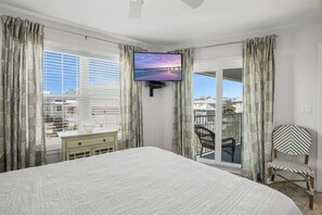 A bedroom with a bed, a TV mounted on the wall, a dresser, a chair, and a balcony with a view. - Walk to the beach-Community Pool/Seasonally Heated (Santa Rosa Beach)