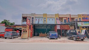 Un immeuble commercial doté de plusieurs devantures de magasins, notamment une pharmacie bien visible et un stand de vente de produits alimentaires.