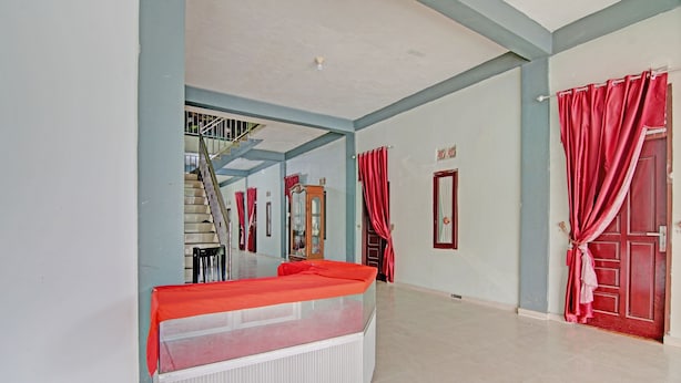 Une pièce spacieuse avec un grand lit, un radiateur, un escalier et des rideaux rouges.