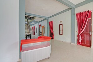 Une pièce spacieuse avec un grand lit, un radiateur, un escalier et des rideaux rouges.