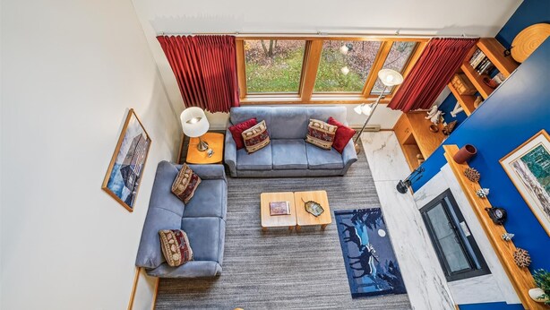 A modern living room with a sectional sofa, a coffee table, and a view of the outdoors through large windows.