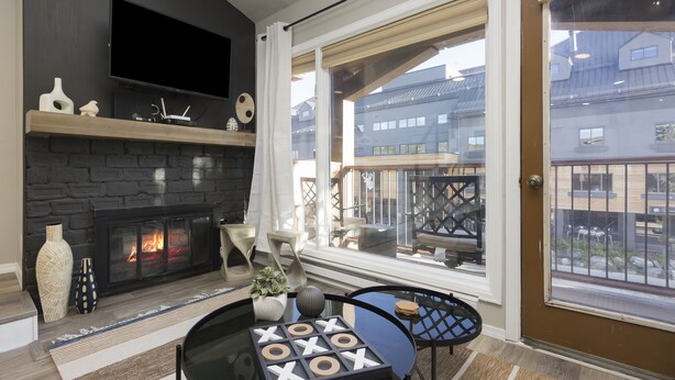 Una sala de estar moderna con chimenea, un televisor de pantalla plana y un balcón con vistas a edificios.