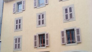 A building with multiple windows, some with shutters, and a door with an orange frame. - Charming flat center and near the lake  (Genève)
