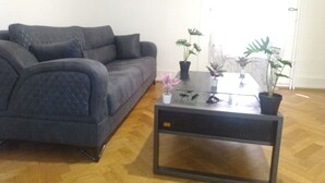 A living room with a grey sofa, a glass coffee table, and several potted plants. - Charming flat center and near the lake  (Genève)