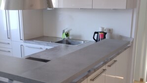 A modern kitchen with white cabinets, a stainless steel sink, and a black bar stool.