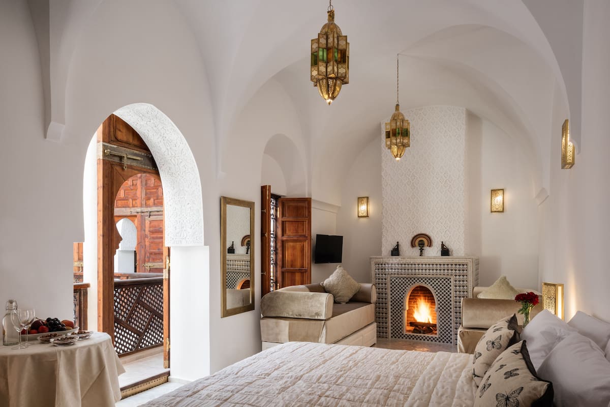 Une chambre avec un lit, une cheminée et une vue sur une cour.