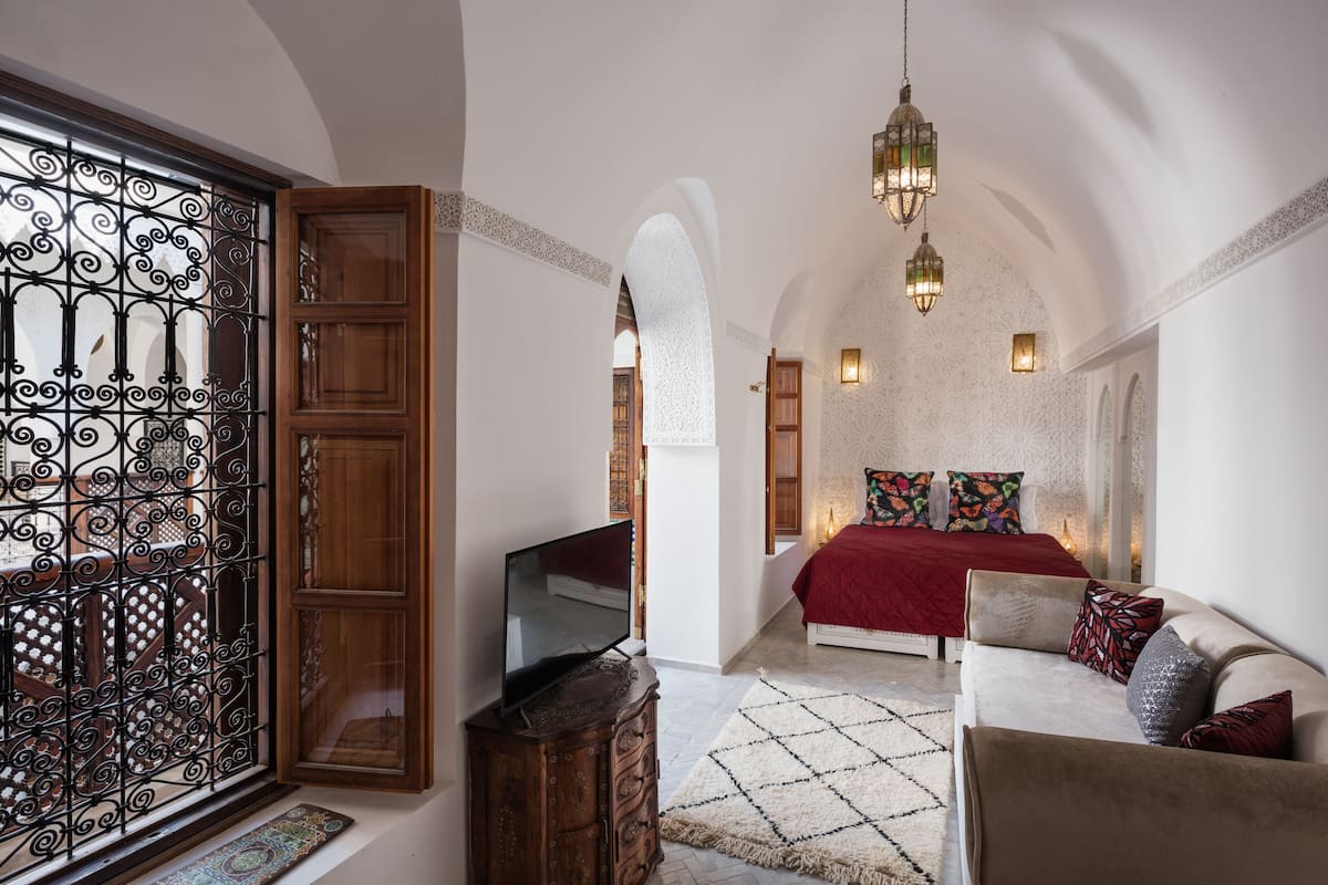 Une chambre avec une télévision, un canapé, un tapis à motifs et une porte décorative.
