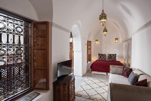 A bedroom with a TV, a sofa, a patterned rug, and a decorative gate. - Riad Spice by Marrakech Riad (Marrakech)