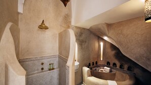 Un baño lujoso con una bañera independiente, ducha empotrada en la pared y un revestimiento decorativo con arcos.