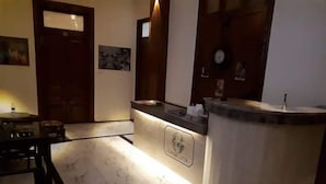 A reception area with a marble floor, a reception desk, a wooden door, and framed pictures on the wall. - Cairo (Cairo)