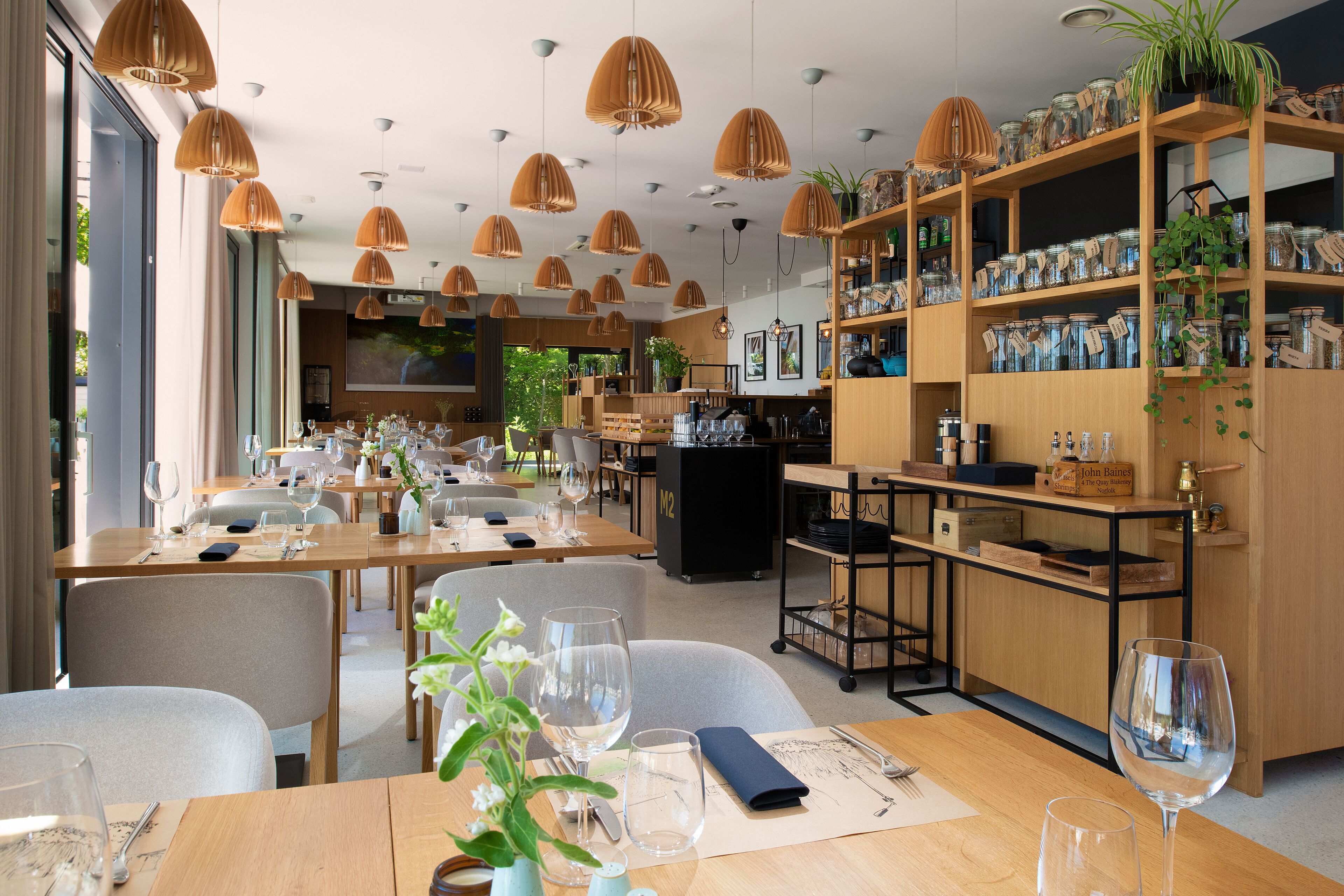 Un restaurante con varias mesas, lámparas colgantes y estantes con frascos.
