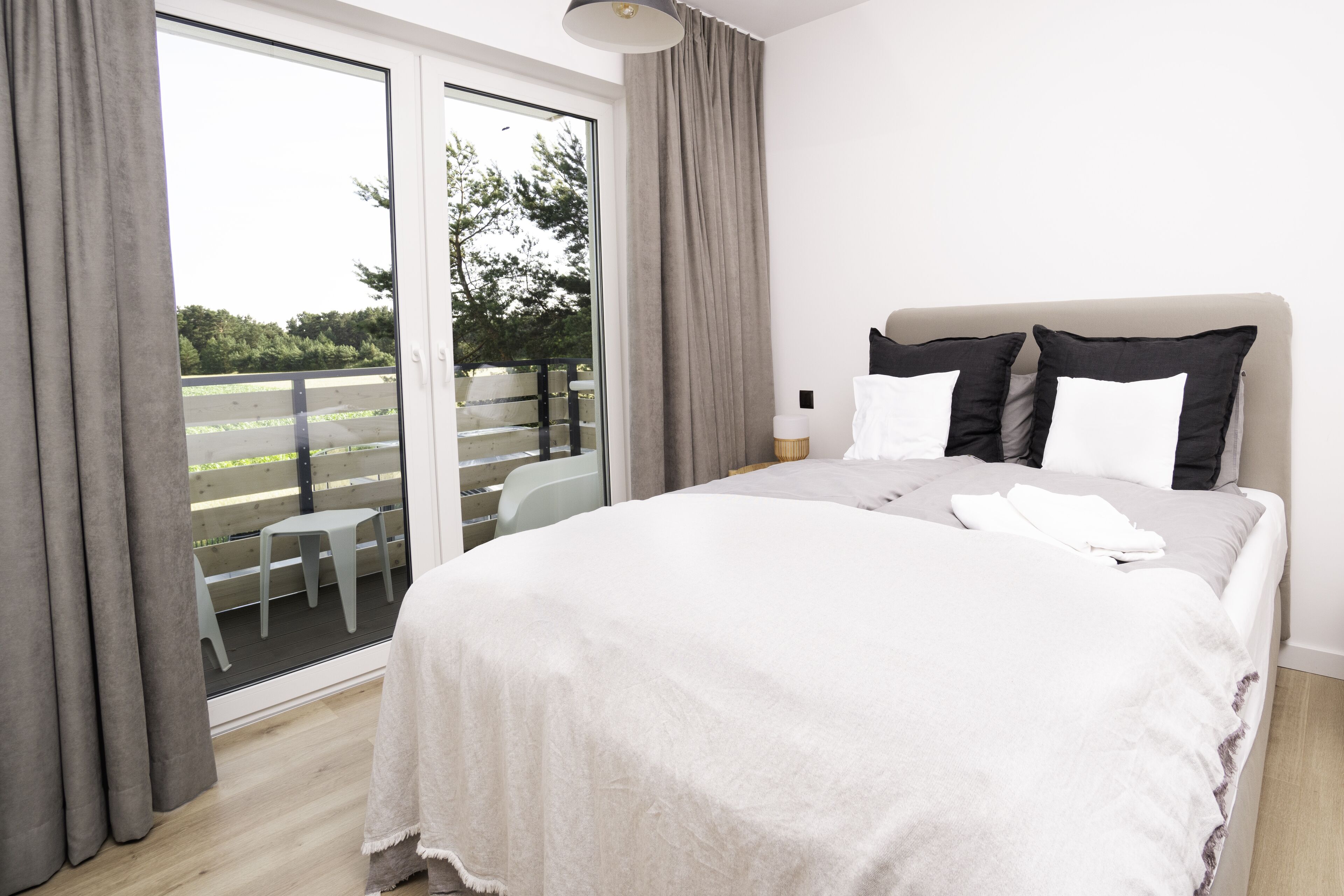 A bedroom with a large bed, a sliding glass door to a balcony, and a small table.