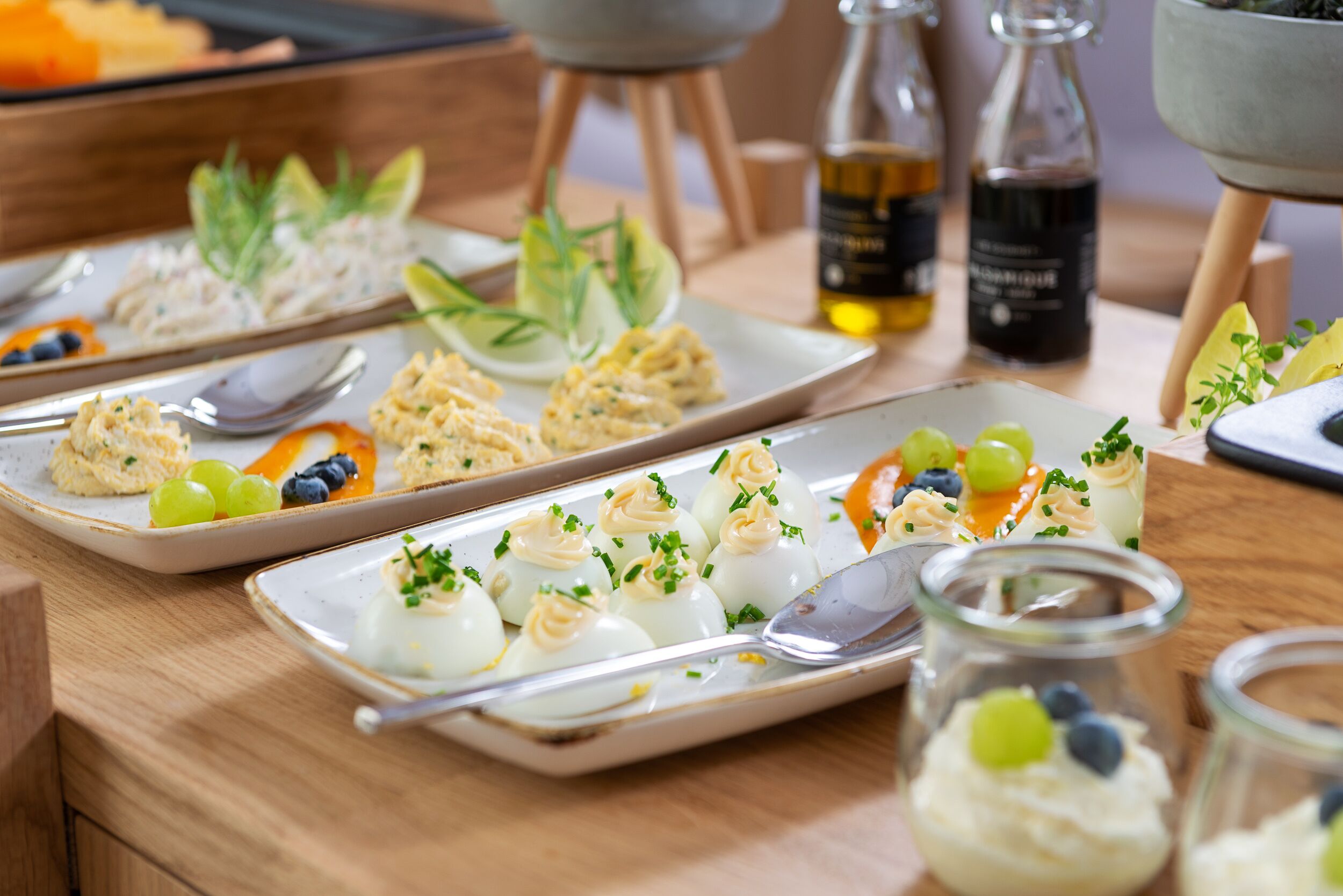 Un tavolo da buffet con diversi cibi, tra cui uova ripiene, frutta e un'insalata.