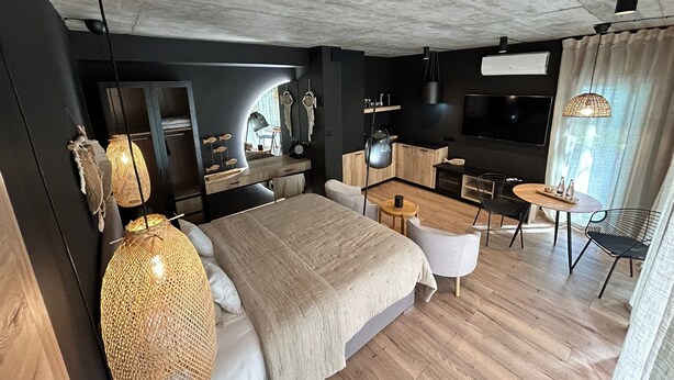 A modern hotel room with a large bed, a desk, a TV, and a dining area. - M2 Resort Wellness & Spa (Wladyslawowo)