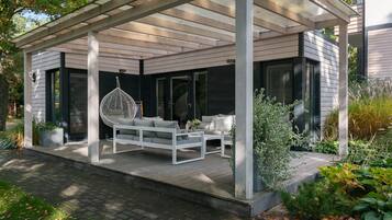 Un espacio de estar al aire libre cubierto con un sofá blanco, una silla colgante y una mesa de centro.