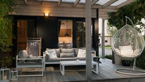 A covered outdoor seating area with a sofa, a hanging chair, and a coffee table. - M2 Resort Wellness & Spa (Wladyslawowo)