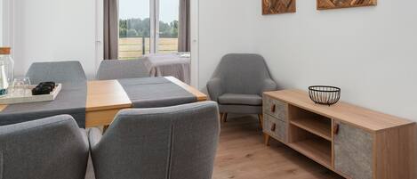 Una habitación moderna con una mesa de comedor, sillas grises, un armario de madera y dos obras de arte en la pared.