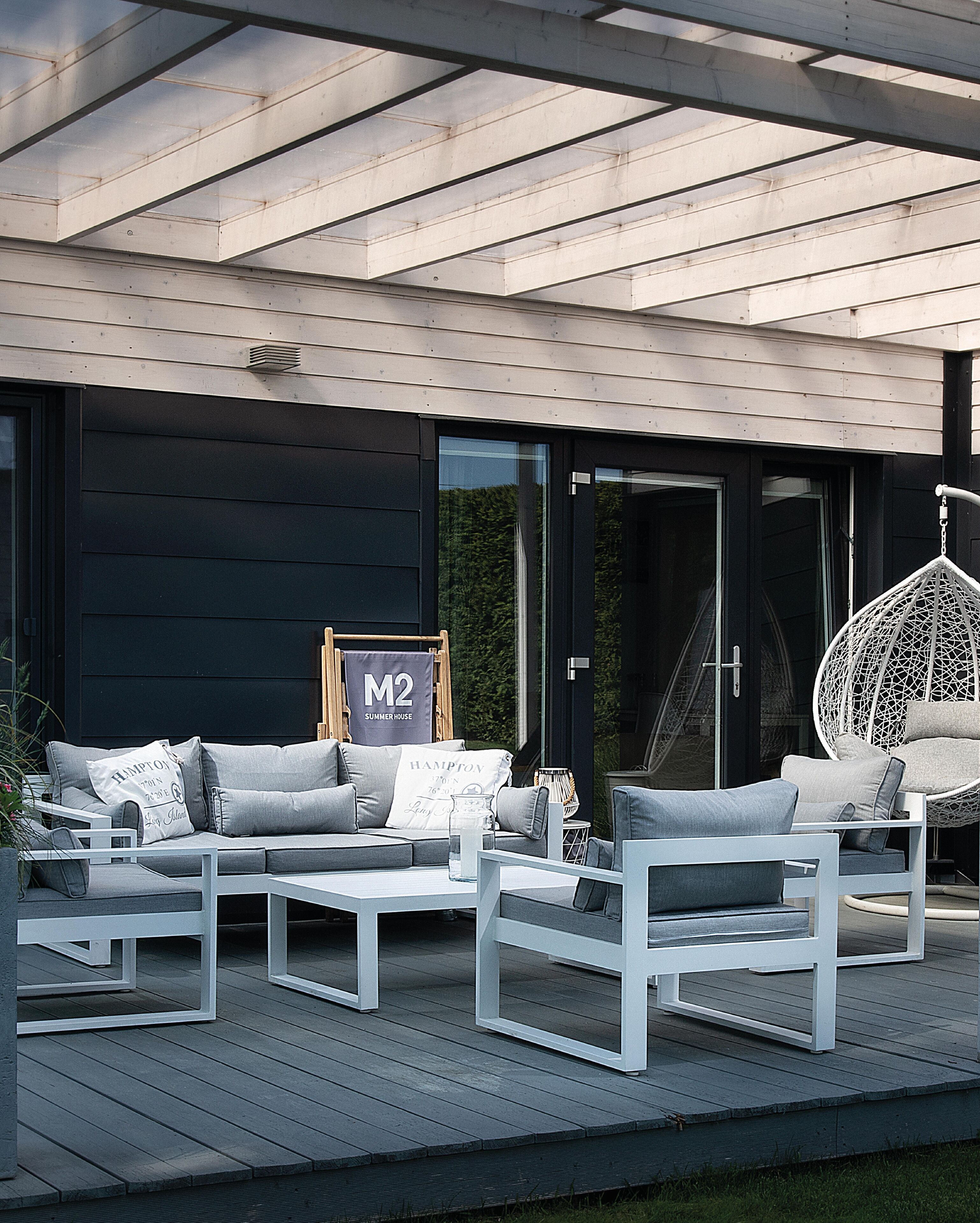 A modern outdoor seating area with a sofa set, a hanging chair, and a coffee table.