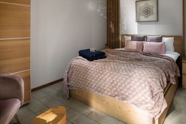 Una cama bien hecha con un edredón estampado, una toalla doblada y dos almohadas con una cita.