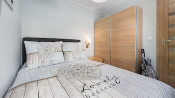 Un dormitorio con cama, mesita de noche, lámpara y armario.