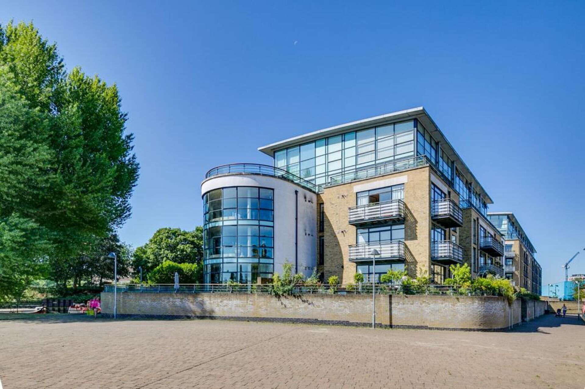 A modern multi-story building with large windows, a curved glass structure, and a brick facade.