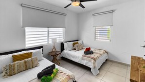 Camera da letto con due letti, una ventola a soffitto e un tavolino con lampada.