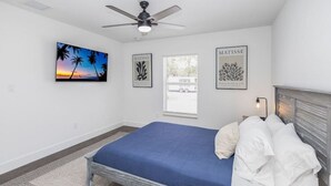 Un dormitorio con cama, ventilador de techo y obras de arte en las paredes.