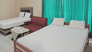 A hotel room with two single beds, a red patterned sofa, and a small table with a white tablecloth. - Capital O 92958 Hotel Raflessia Syariah (Lawang Kidul)