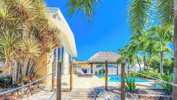 A resort with a pool, lounge chairs, and tropical plants. - Happy Tingler With Pool Tiki and 100 ft of Dockage Right Next to Sombrero Beach (Marathon)