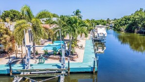 A dock with a pool, palm trees, and a boat. - Happy Tingler With Pool Tiki and 100 ft of Dockage Right Next to Sombrero Beach (Marathon)