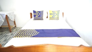 A bed with a wooden frame, a white mattress, and a blue and yellow patterned bedspread.