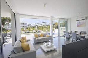 A modern living room with a sofa, coffee table, and dining area. - Villa Nancy, Stunning 3BDR Protaras Villa with Pool, Close to the Beach (Protaras)