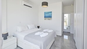 Une chambre d’hôtel moderne équipée d’un lit, d’une table de chevet, d’un climatiseur et ornée d’un tableau au mur.