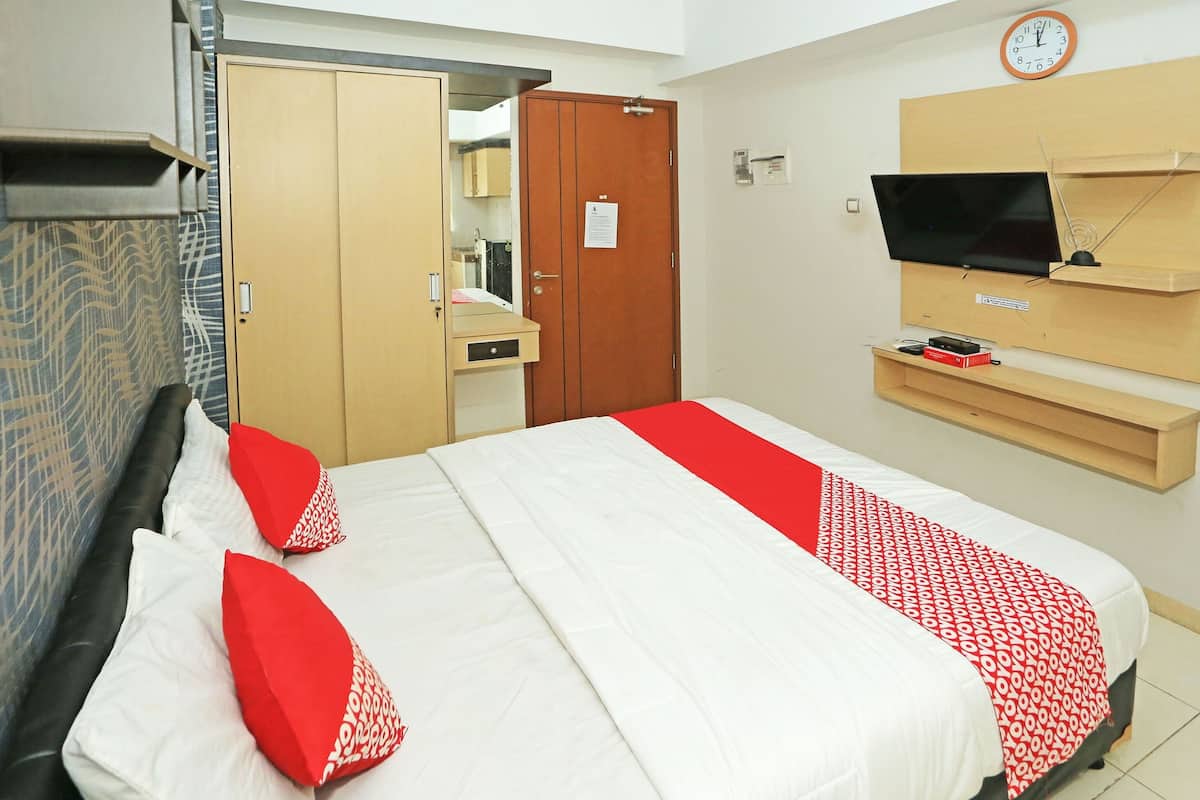 Een hotelkamer met een bed, een kledingkast, een televisie en een klok aan de muur.