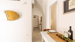 A dining area with a table set for two, a bottle of wine, and a decorative tray with fruits and herbs. - 3482 Vico dei Mille by Barbarhouse (Tuglie)
