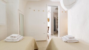A hotel room with two beds, each with a folded white towel, a mirror, and a door leading to a bathroom. - 3482 Vico dei Mille by Barbarhouse (Tuglie)